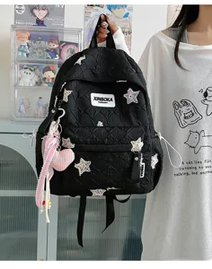 Vue détaillée du sac à dos noir matelassé avec broderie d'étoiles et pendentif rose.