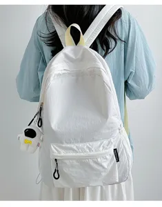 Vue détaillée d'un sac à dos léger blanc décontracté avec poche avant et pendentif astronaute.