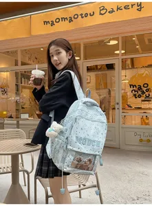 Vue détaillée du sac à dos bleu clair à motif étoilé avec poche transparente et joli pendentif.