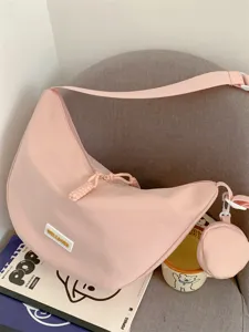 Nahaufnahme der stilvollen rosafarbenen Dumpling Umhängetasche mit Mini-Tasche auf grauem Stuhl