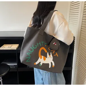 Canvas shoulder bag detail showing cute cat graphic and side pouch in lifestyle setting.