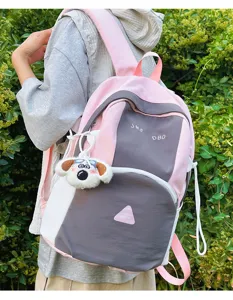 Cute colorblock backpack detail showcasing trendy pink grey design and lovely plush dog pendant.