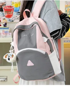 Detail view of the pink and grey colorblock backpack showing zipper compartments and cute charm.