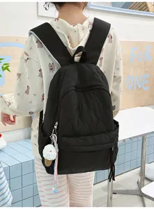 Détail du sac à dos matelassé noir avec larges bretelles et joli porte-clés glace mignon.
