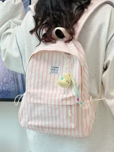Detail view of the pink striped canvas backpack featuring a cute plush pendant and pockets.