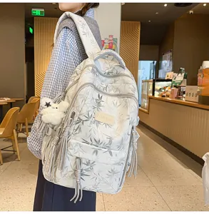 Detail shot of a large-capacity canvas backpack with bamboo leaf print and cute plush pendant.