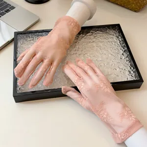 Close-up of women's sheer lace sun protection gloves with floral patterns and mesh fabric.