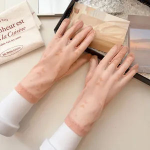 Detail view of sheer mesh sun protection gloves with delicate bow patterns for summer.