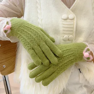 Guanti in maglia verde dettaglio, tessuto morbido, pon pon rosa, calda moda invernale.