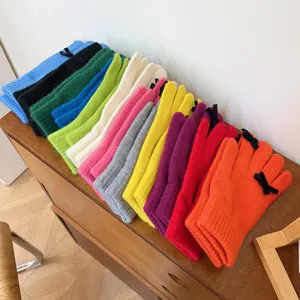 Detailed shot of colorful knit gloves with cute black bows neatly arranged on a wooden table.