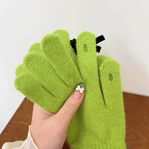 Detailed view of women winter warm green knit gloves, featuring bow and touchscreen.