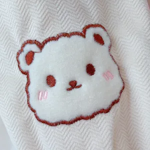 Detail view of cute bear embroidery on winter warm sleeve cuffs, soft plush fabric texture.