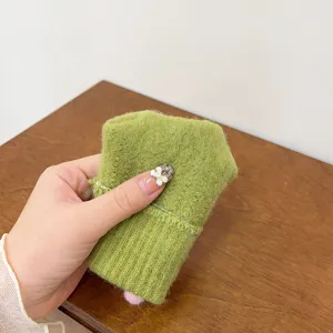 Primo piano dettagliato di morbidi guanti invernali in maglia verde da donna con trama accogliente.