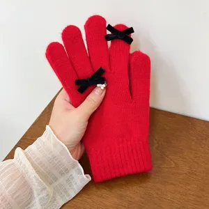 Close-up detail of red knitted gloves with elegant black velvet bows for winter.