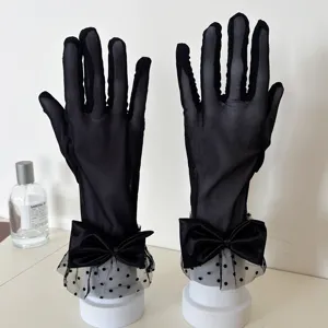 Detailed close-up of black mesh polka dot lace gloves with elegant satin bow design.