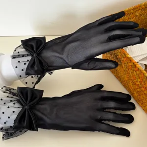 Detailed shot of black sheer mesh gloves with elegant polka dots and cute satin bows for women.