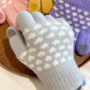 Detailed shot of winter warm knitted touchscreen gloves with cute heart patterns for women.