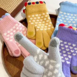 Close-up of women's sweet knitted warm gloves with heart pattern and touch screen design.