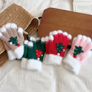 Detailed shot of fluffy winter Christmas tree gloves with warm fleece lining and cute pom-poms.