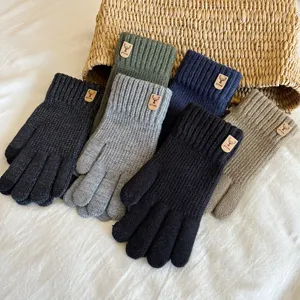 Close-up detail of knitted touchscreen gloves with deer logo in multiple cozy colors.
