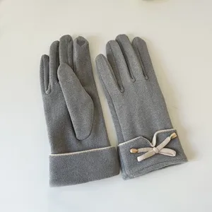 Detail view of winter warm grey touchscreen gloves with cute bow cuff design, soft fabric.