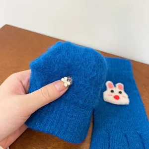 Close-up of fluffy knit blue winter gloves with cute rabbit patch, soft and warm texture detail.