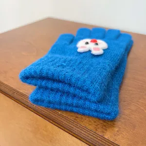 Detailed view of winter blue knit gloves featuring a cute rabbit decoration for cold weather.