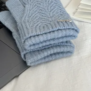 Detail view of winter knitted gloves in light blue, featuring cozy wool texture and metal accent.