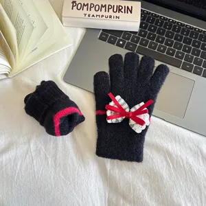 Detail view of black knit touch screen gloves featuring red stripe and lace bow decoration.