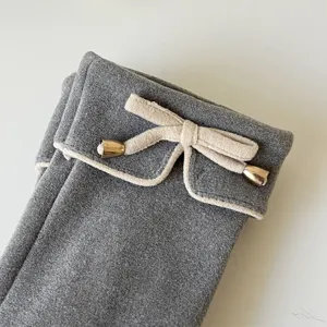 Grey winter thermal gloves with elegant beige trim bow and metal tips for cold weather.