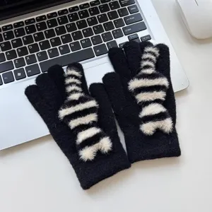 Detailed close-up shot of winter warm black knitted gloves featuring cute furry striped cat tail.