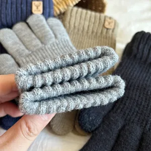 Close-up of winter knitted touchscreen gloves cuff with deer logo tag, ribbed texture.