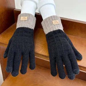 Close-up detail of women's winter knit touchscreen gloves in black and grey with label.