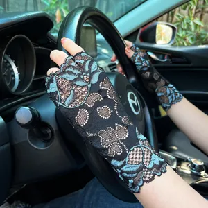 Close-up detail of women's black and blue lace fingerless driving gloves worn in car.