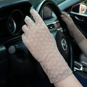 Close-up detail of women's beige floral lace UV protection driving gloves in summer car view.