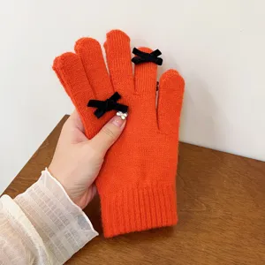 Orange knit winter gloves featuring cute black velvet bows. Soft wool material, warm five-finger.