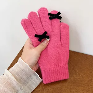 Detailed view of women's winter knit warm gloves in solid pink with chic black velvet bows.