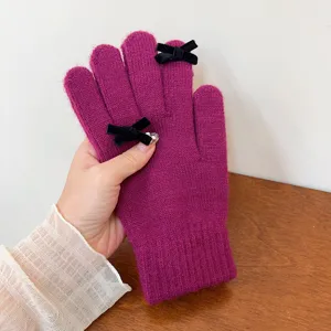 Fuchsia knitted five-finger winter gloves with chic black velvet bow details for cold weather.