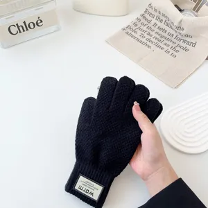 Close-up detail of winter warm knit gloves in black, featuring textured fabric and elastic cuff.
