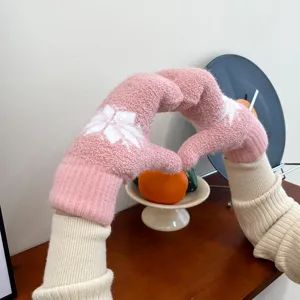 Detailansicht kuscheliger rosa Winter-Strickfäustlinge mit einem süßen weißen Schneeflockenmuster.