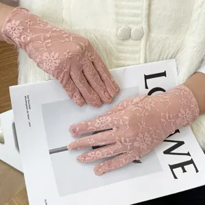Gros plan détaillé de gants de protection solaire en dentelle rose délicate à motif floral.