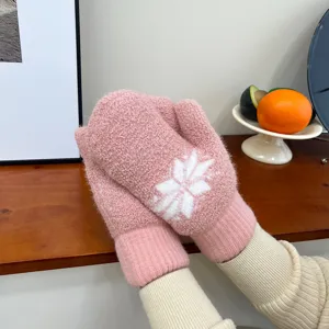 Detailaufnahme kuscheliger rosa Plüsch-Winterhandschuhe mit weißem Schneeflockenmuster.