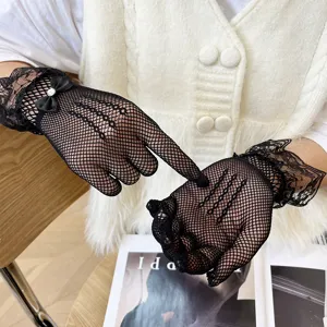 Detailed view of women black lace fishnet gloves with cute bow and rhinestone, sexy and elegant.