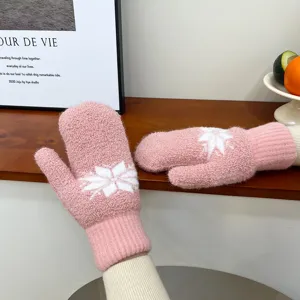Gemütliche rosafarbene flauschige Winterfäustlinge mit filigranem Schneeflocken-Muster im Detail.