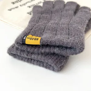 Detail view of dark grey knitted warm gloves with yellow label accent for winter daily wear.