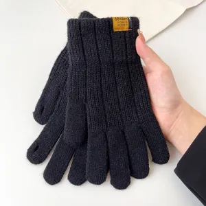 Close-up detail shot of winter knitted touch screen gloves in black with cuff label accent.