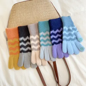 Detailed shot of multi-color knitted touchscreen gloves with wave stripes over a straw bag.