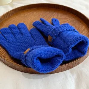 Close-up of blue winter knit gloves on a wooden tray, showing soft texture and ribbed cuff.