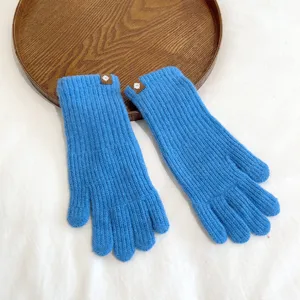 Detailed shot of blue knit gloves with decorative cuffs, soft warm winter accessory.