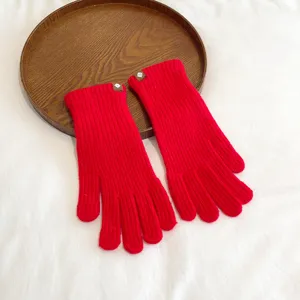 Red knit glove detail showing textured fabric and small cuff tag, perfect for winter warmth.